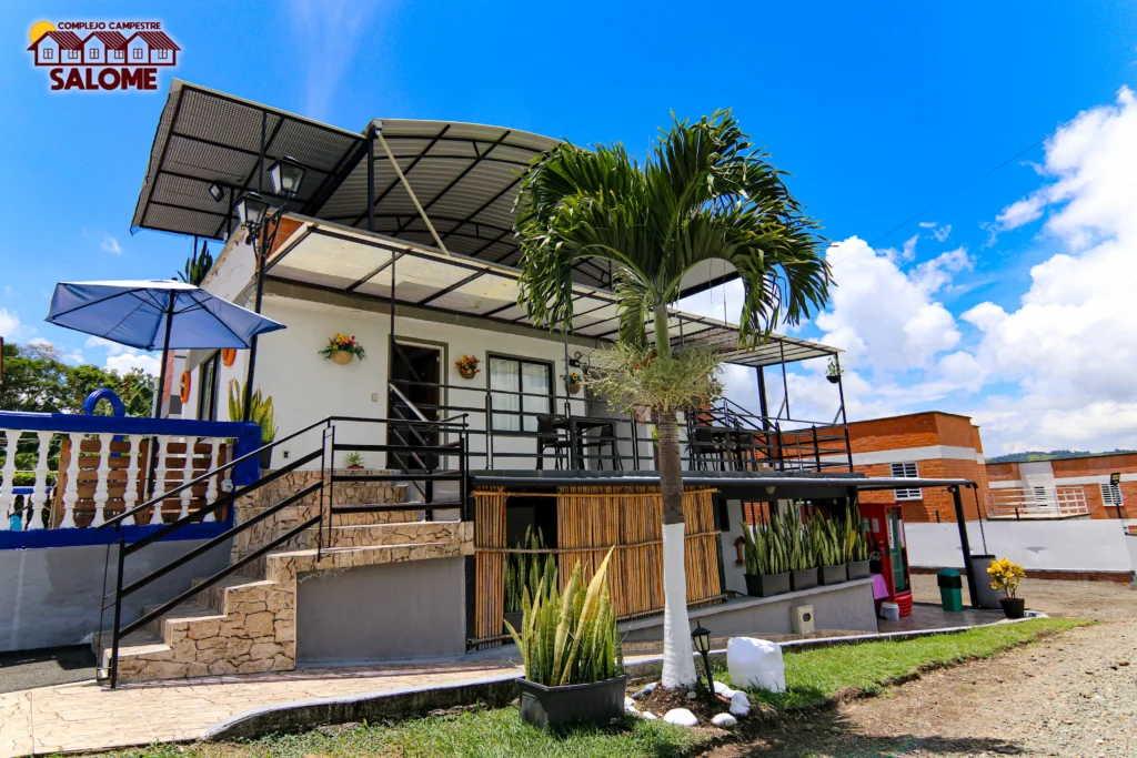 Edificio principal de Salome, alojamiento campestre con jardín exuberante y cielo azul, ideal para Lago Calima.