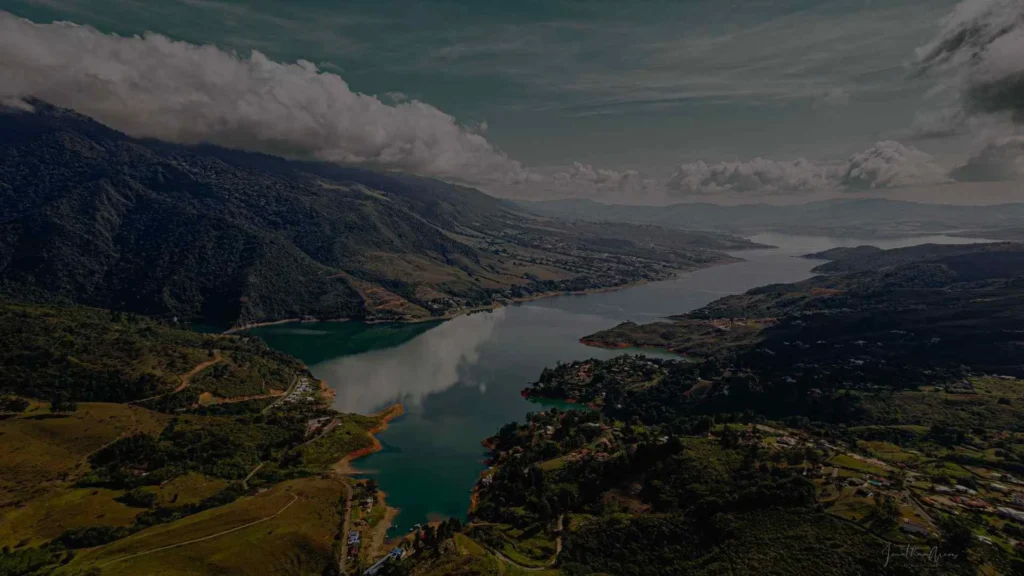 Cómo Llegar Al Lago Calima Desde Cali: Guía Completa Para Viajeros 7 Impresionante paisaje del Lago Calima, un embalse de aguas verdes enmarcado por colinas frondosas y cielos nublados.