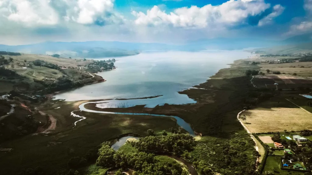 Cómo Llegar Al Lago Calima Desde Cali: Guía Completa Para Viajeros 6 Hermosa vista panorámica del Lago Calima, con colinas verdes y un río serpenteando hacia el gran cuerpo de agua.