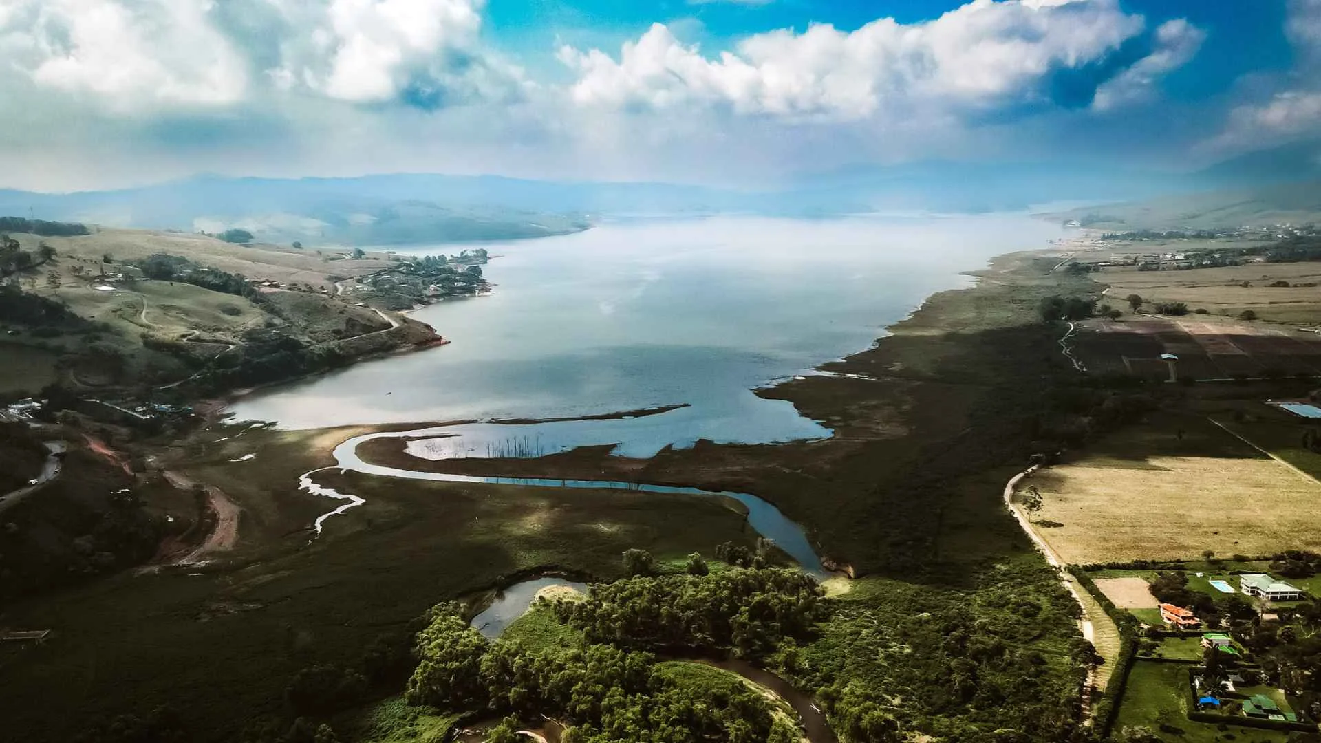 Hermosa vista panorámica del Lago Calima, con colinas verdes y un río serpenteando hacia el gran cuerpo de agua.