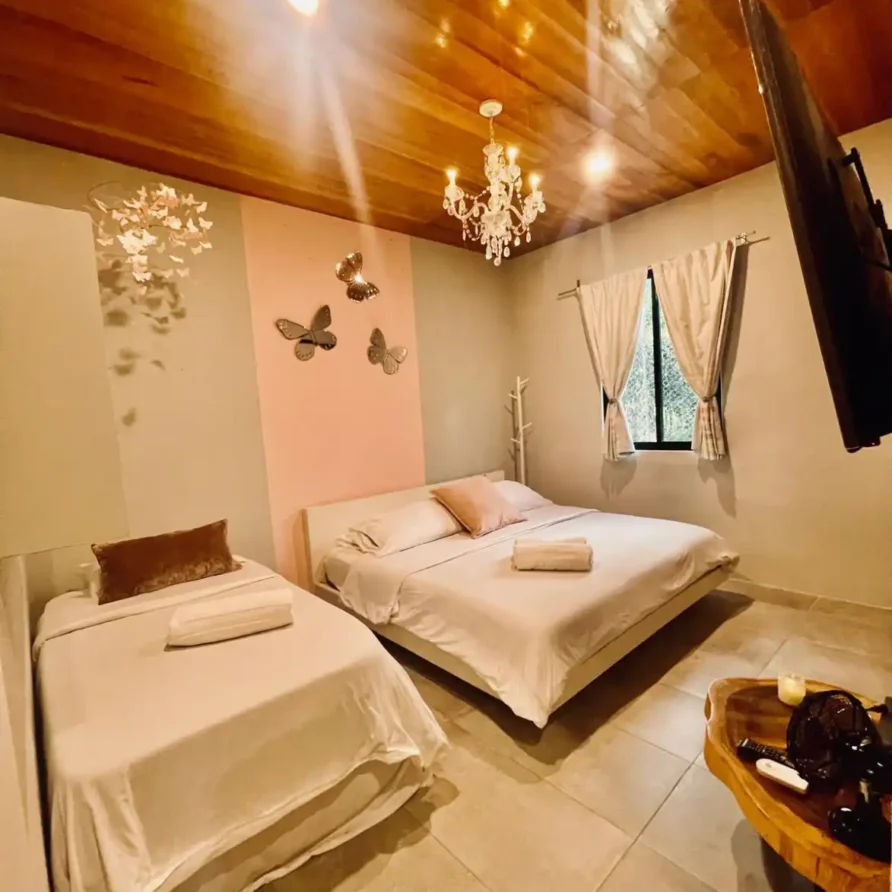 Habitación de casa campestre en Lago Calima con cama doble, cama individual, techo de madera y decoración de mariposas.