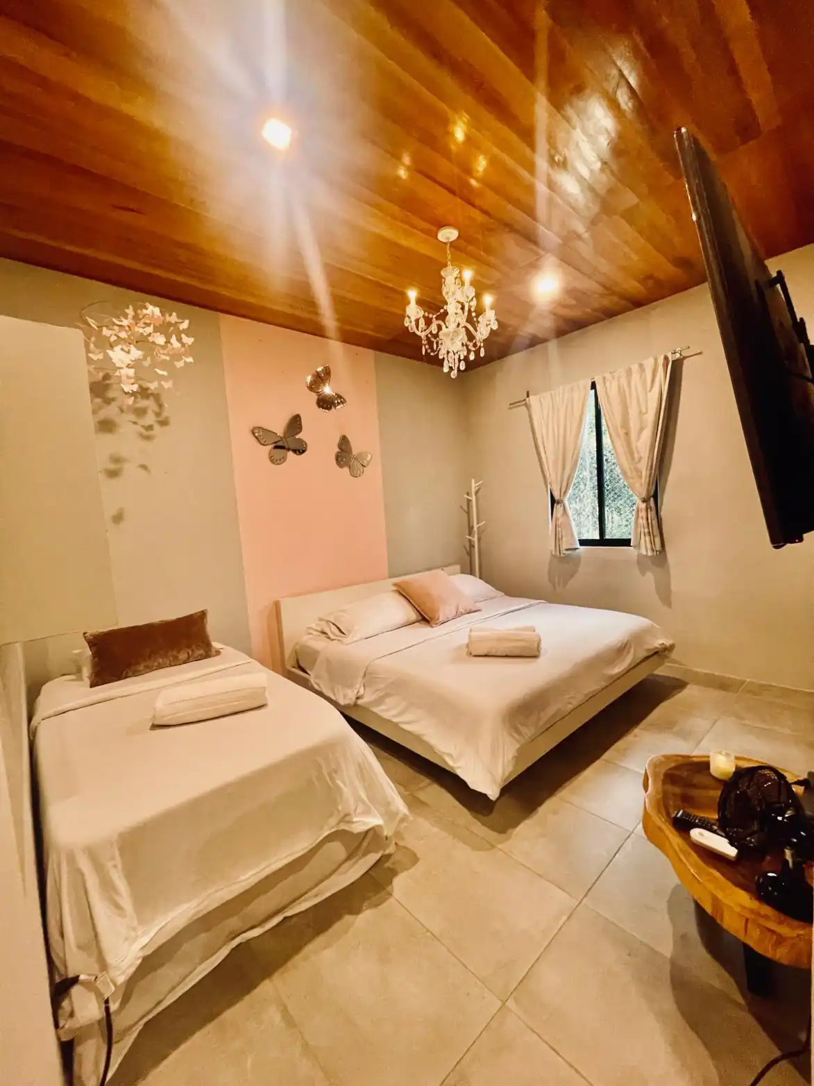 Habitación de casa campestre en Lago Calima con cama doble, cama individual, techo de madera y decoración de mariposas.