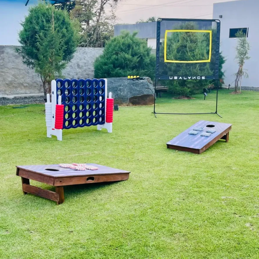 Juegos al aire libre en el jardín de una casa campestre en Lago Calima: Connect Four, cornhole y red de práctica.