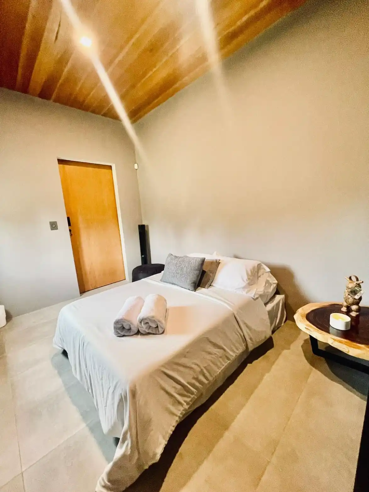 Dormitorio moderno en casa campestre con techo de madera y cama blanca, ideal para descanso cerca de Lago Calima.