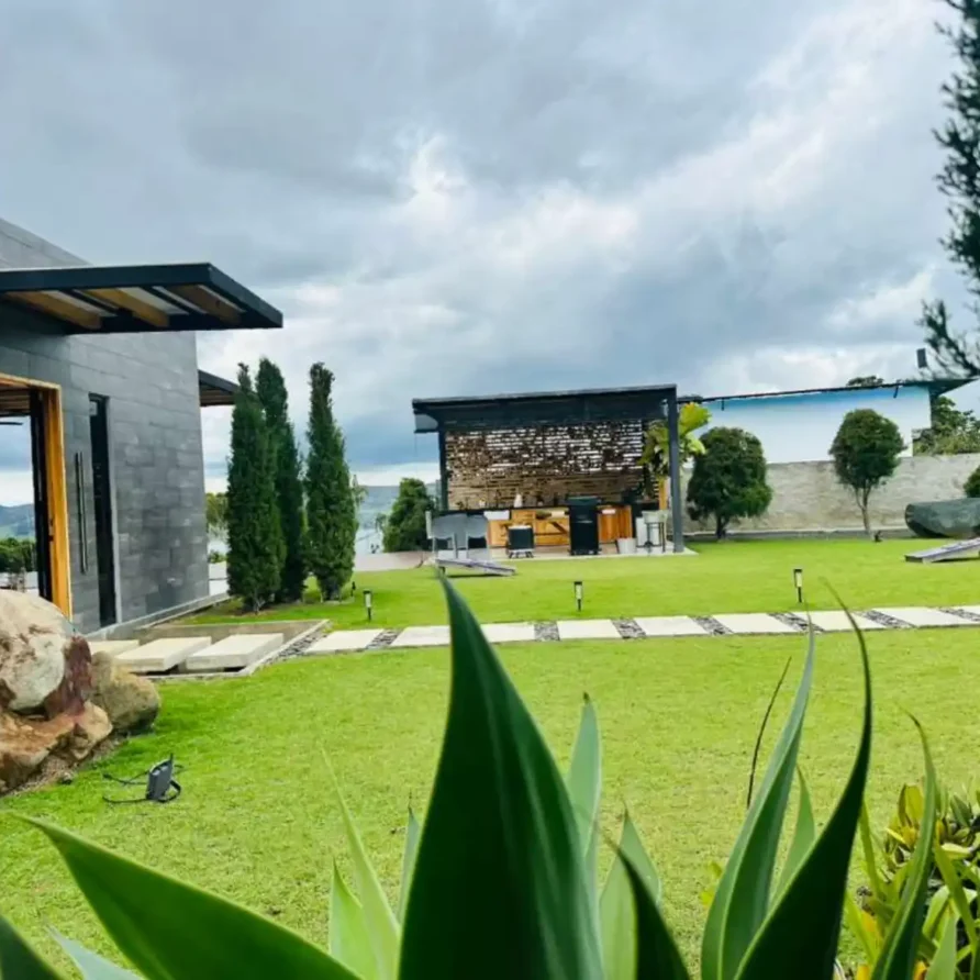 Hermosa casa de campo con césped cuidado, rocas decorativas y área de parrilla junto al lago Calima.