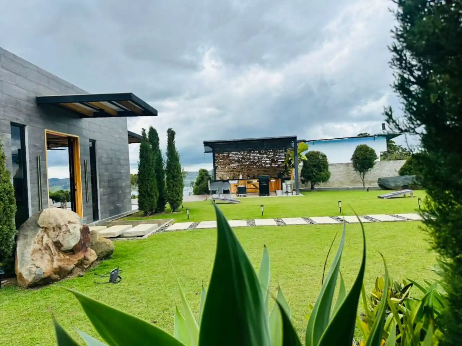 Hermosa casa de campo con césped cuidado, rocas decorativas y área de parrilla junto al lago Calima.