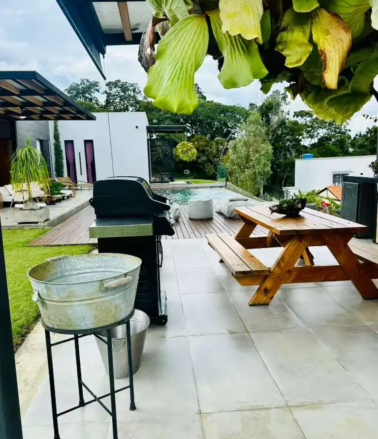 Patio moderno de casa campestre con piscina, parrilla BBQ y mesa de pícnic. Ideal para relax y reuniones.