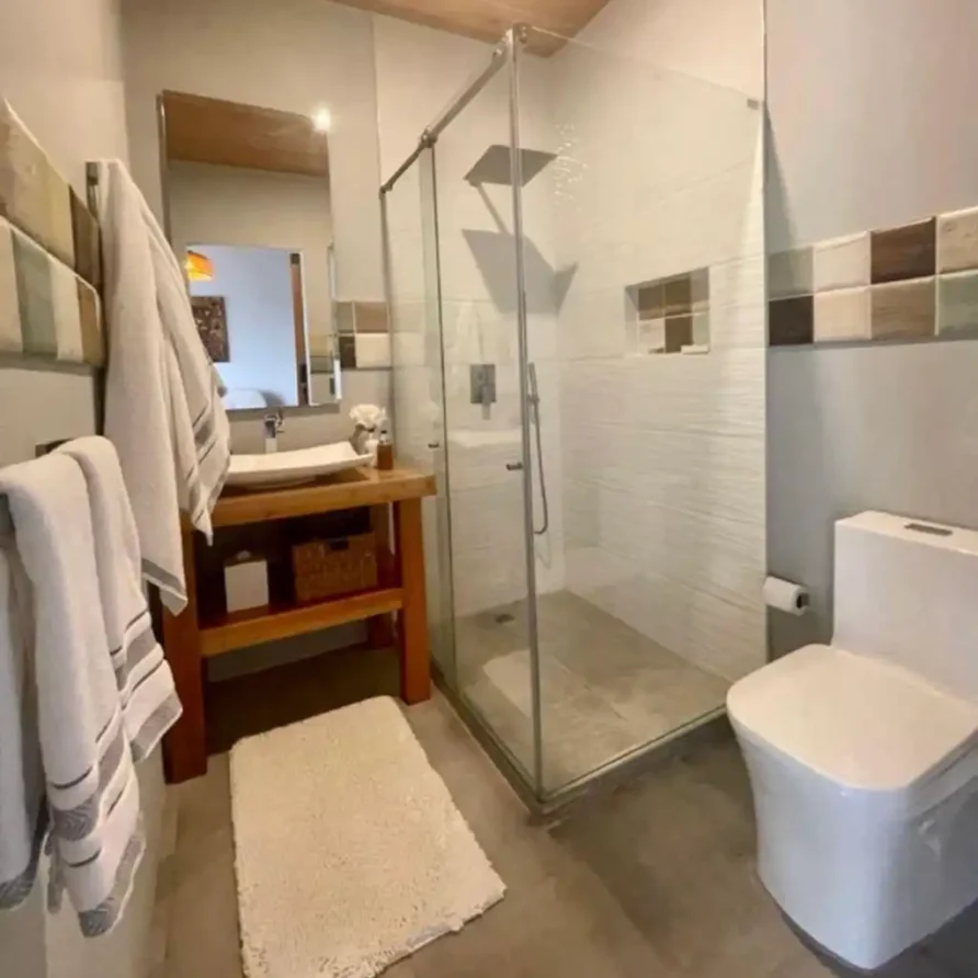 Baño moderno con ducha de cristal, lavamanos de madera y toallas, ideal para casa campestre Lago Calima.