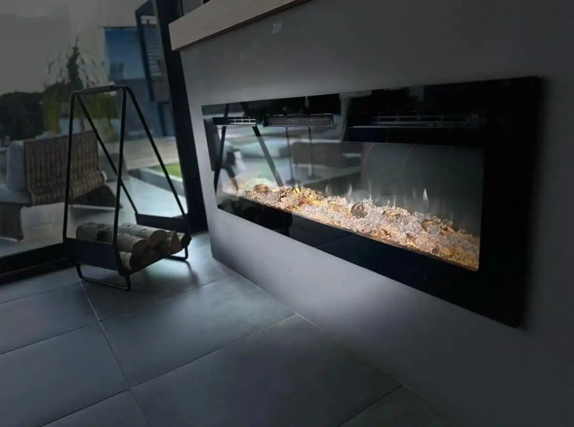 Chimenea de diseño contemporáneo con efecto de fuego y cristales, junto a un porta leña en hogar Kommo.