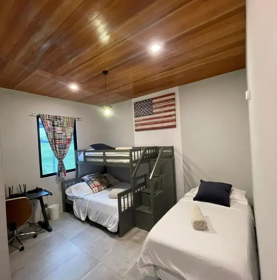 Habitación casa campestre Lago Calima con litera doble, cama individual, techo de madera y bandera de USA.