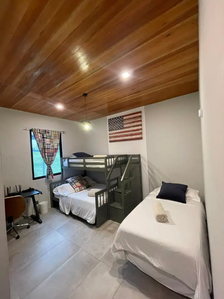Habitación casa campestre Lago Calima con litera doble, cama individual, techo de madera y bandera de USA.