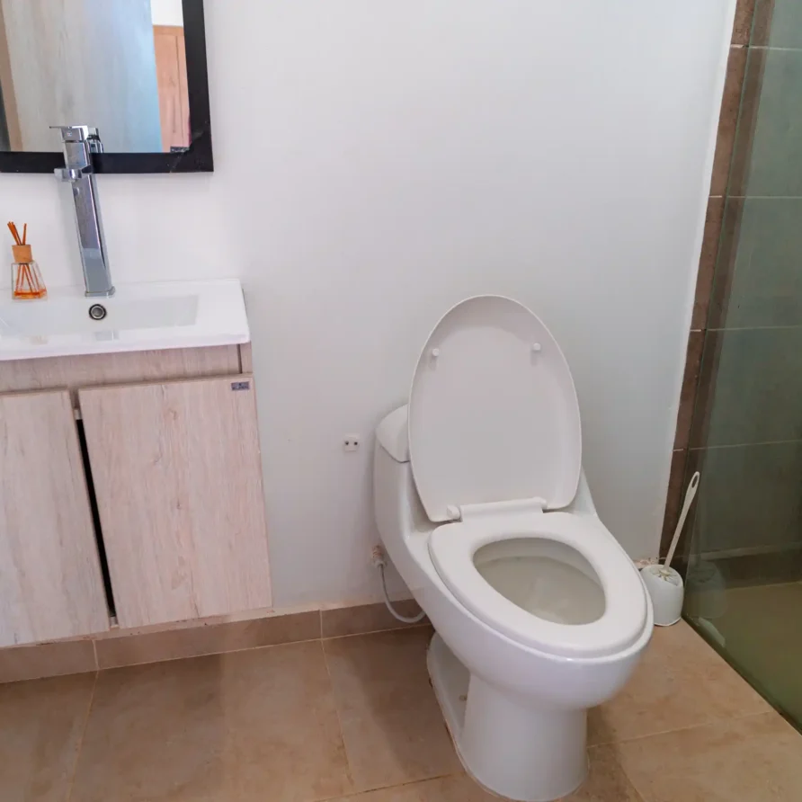 Baño moderno y luminoso con lavabo, inodoro y ducha, parte de una casa o cabaña cerca de Lago Calima.