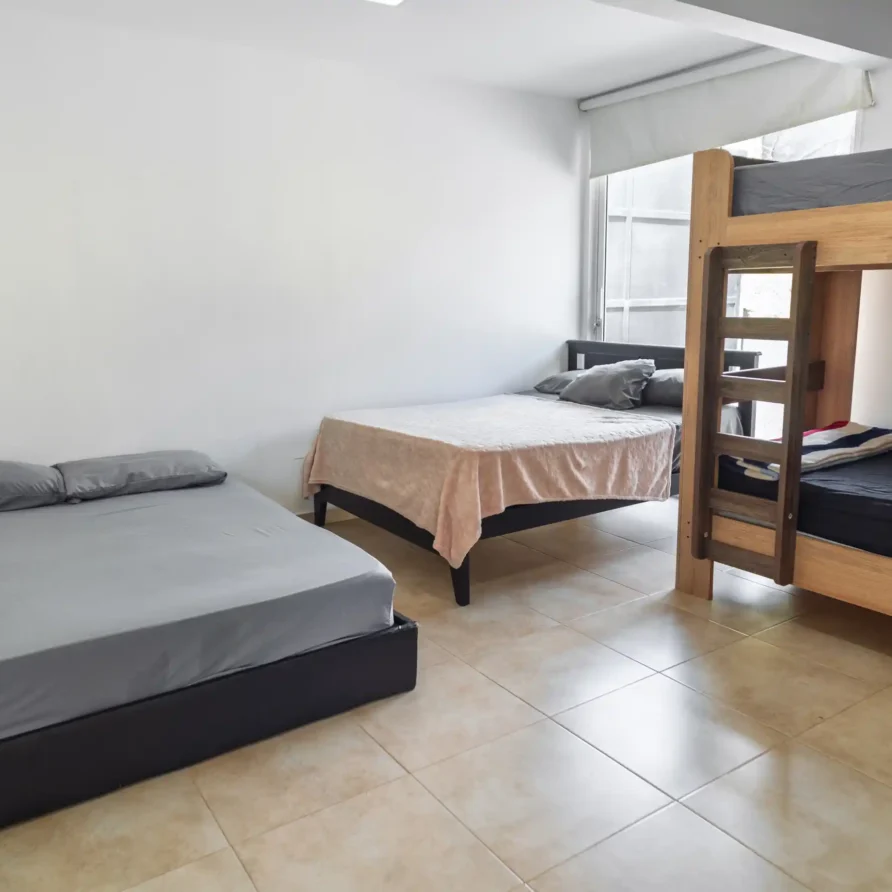 Dormitorio con cama doble, cama individual y litera de madera, ideal para hospedaje familiar o de grupo en Lago Calima.