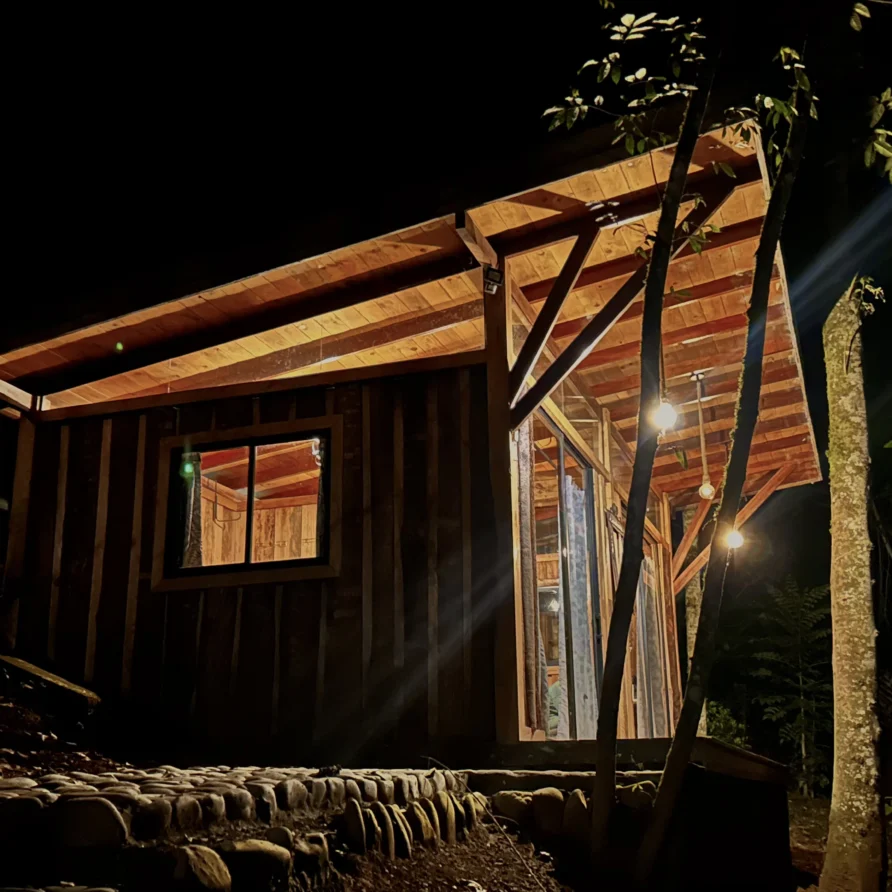 Planes Turisticos 107 Cabaña de madera iluminada en la oscuridad del bosque, ideal para una escapada romántica cerca del Lago Calima.