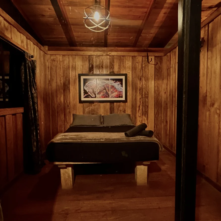Planes Turisticos 108 Acogedor dormitorio de cabaña de madera con cama doble, ropa gris, luz cálida. Ideal para pareja cerca de Lago Calima.