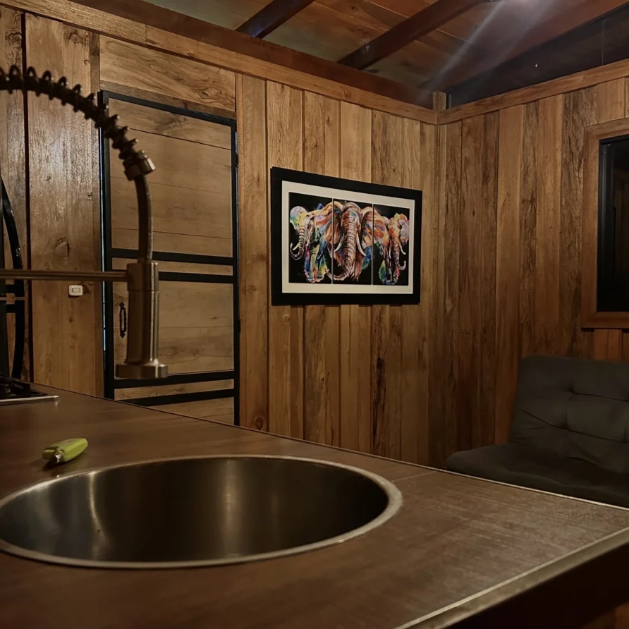 Planes Turisticos 111 Cocina y sala de estar en cabaña 'Crisálida' cerca del Lago Calima, con detalles de madera y arte vibrante.