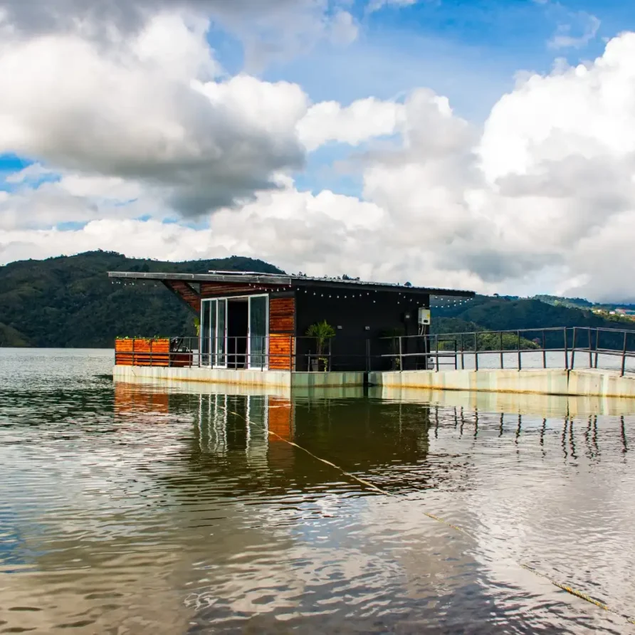 Glamping flotante moderno sobre el Lago Calima, Colombia, con diseño contemporáneo y vistas a montañas verdes.