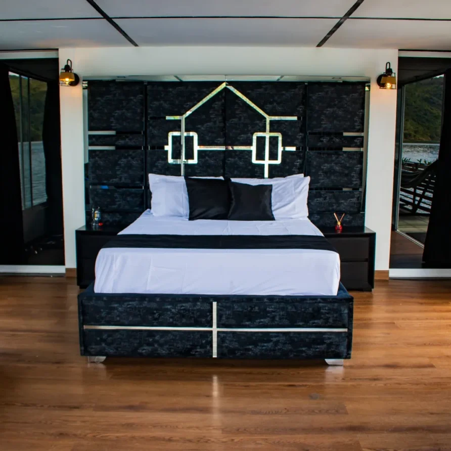 Interior lujoso de glamping flotante sobre el Lago Calima, cama doble y decoración en blanco y negro.