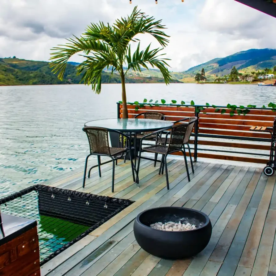 Glamping flotante en Calima El Darién, Colombia: deck de madera con mobiliario exterior y red de relajación sobre el agua.