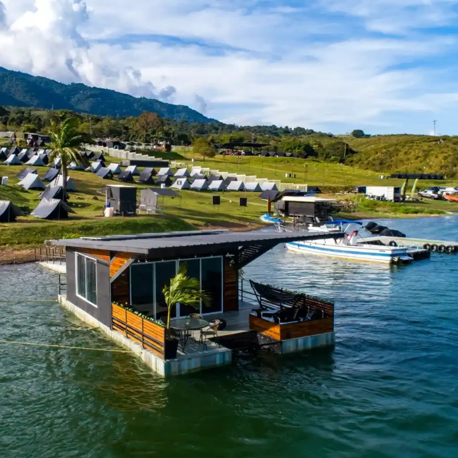 Glamping flotante en el Lago Calima, Calima El Darién, Colombia, con campamento de tiendas y montañas de fondo.