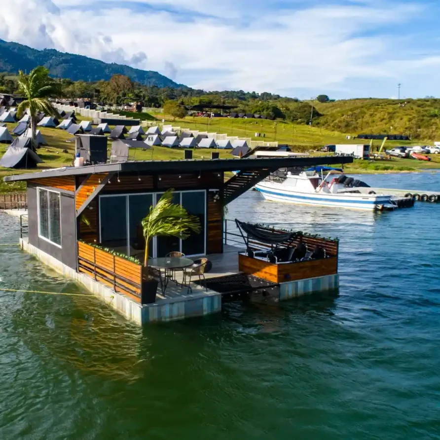Vista aérea de un glamping flotante en el Lago Calima, Calima el Darién, con barco y colinas verdes.